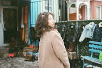 a woman in a brown coat standing in front of a store